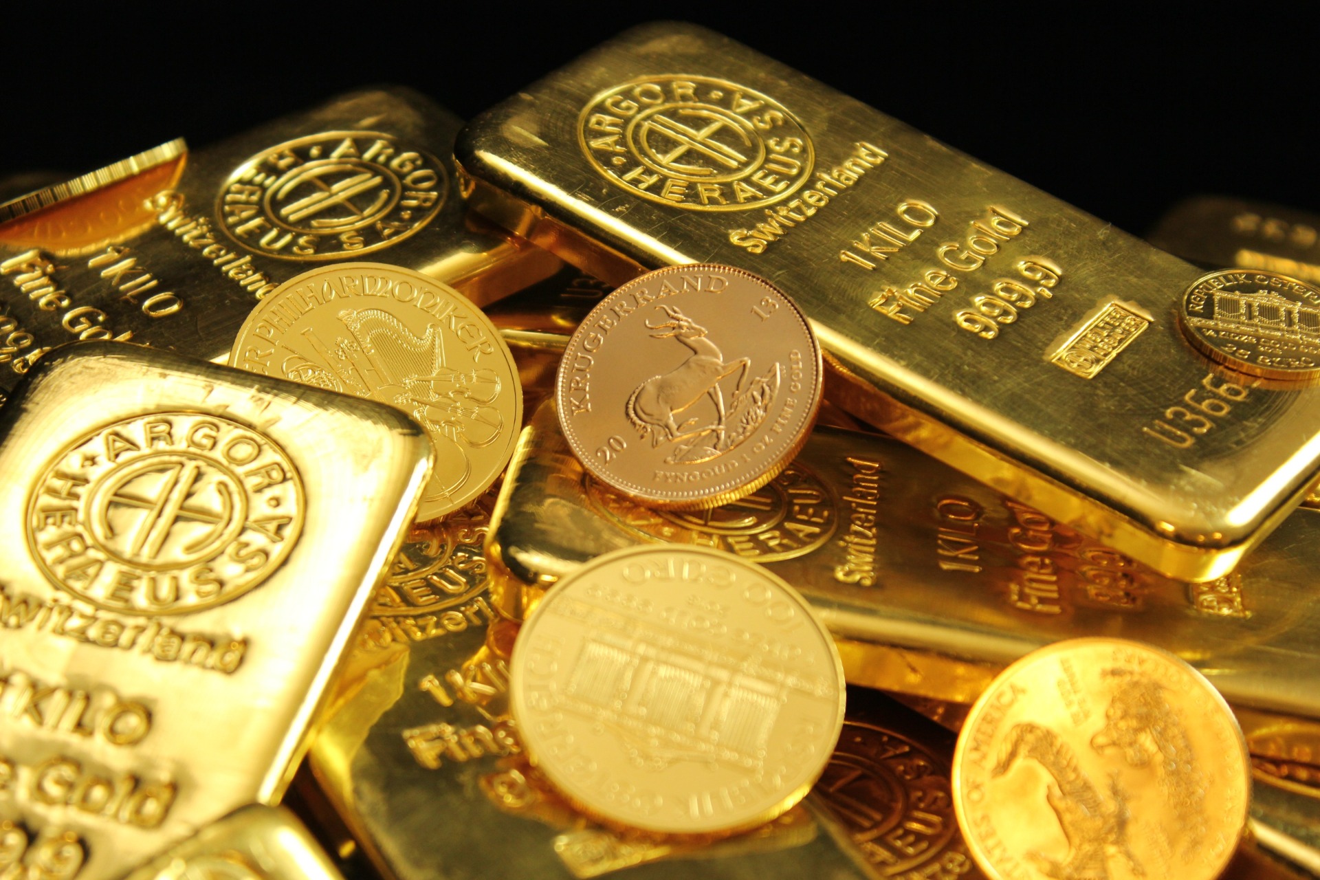 Close-up of gold bars and coins featuring Bitcoin logos and “1 oz” markings.